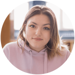 Emily smiles in front of a classroom.