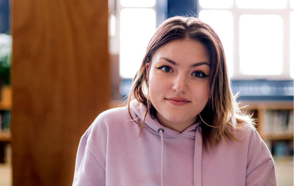 A photo of Emily sitting in a school library.