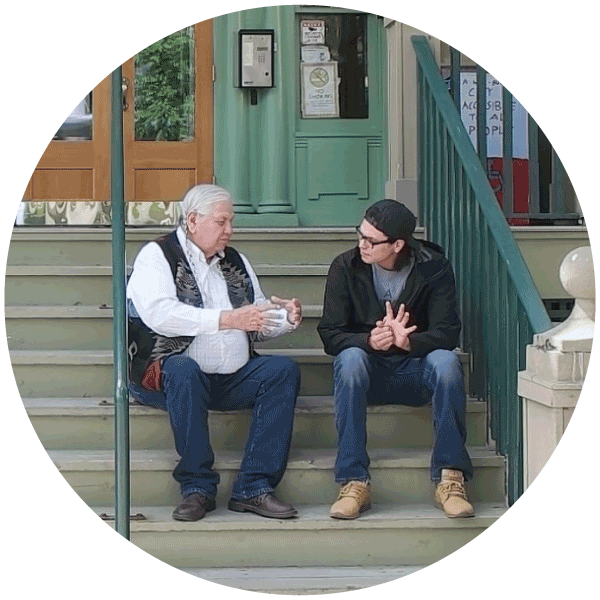 Reg and Johnny sit on the steps in front of the Diamond Willow Youth Lodge