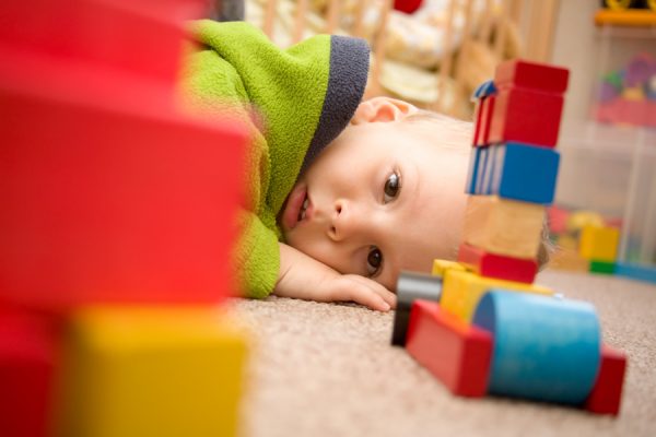 A toddler looks at blocks on the floor