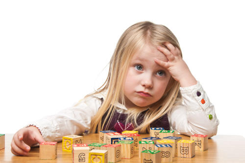 A child looks puzzled while playing with blocks