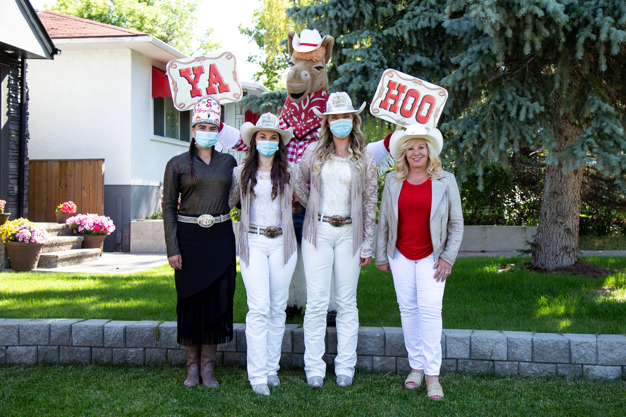 Group shot of the Stampede Princess' with Harry the Horse holding Ya Hoo signs