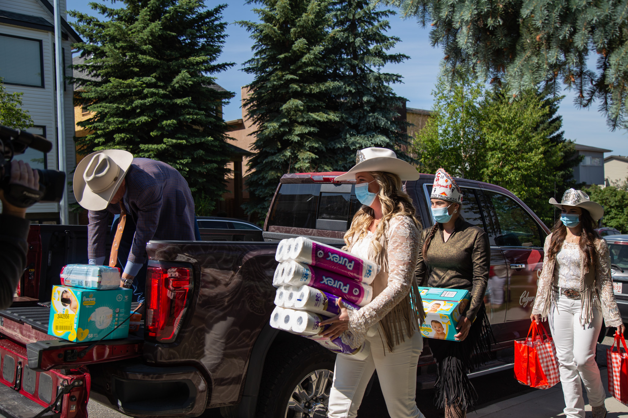 Group shot of the Stampede Princess' loding donation items and toilet paper into the back of a truck on a sunny day
