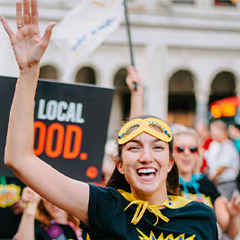 women raising her hand celebrating with a happy group of people in a Calgary parade