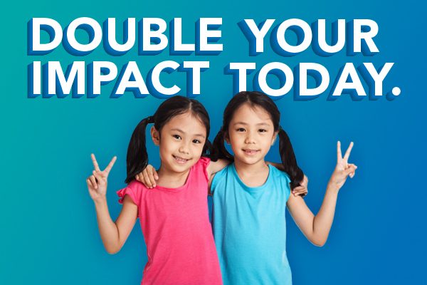 Twins hold up peace signs, text reads, `` Double your impact today.``